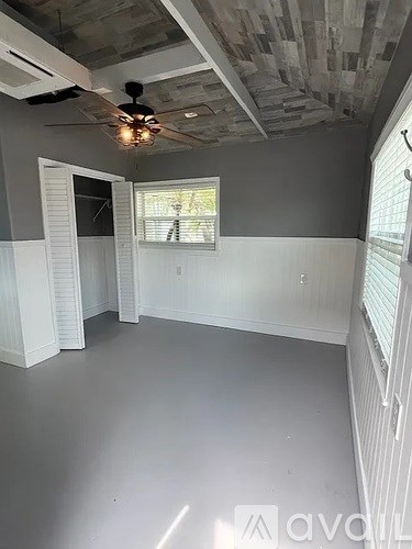 A room with a ceiling fan and a window with blinds.