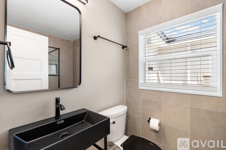 A bathroom with a black sink and a toilet paper roll on the wall.