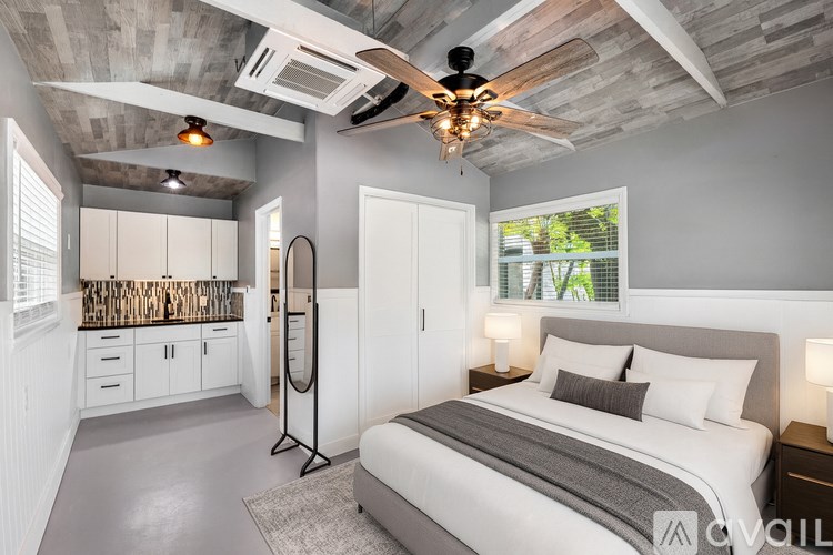 A bedroom with a bed, a ceiling fan, and a window with blinds.