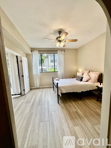A bedroom with a bed, a ceiling fan, and a window with curtains.