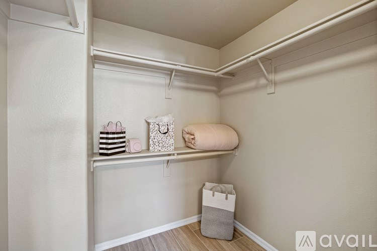A room with a wooden floor, a ceiling fan, a chair, a table, a rug, and a mirror.