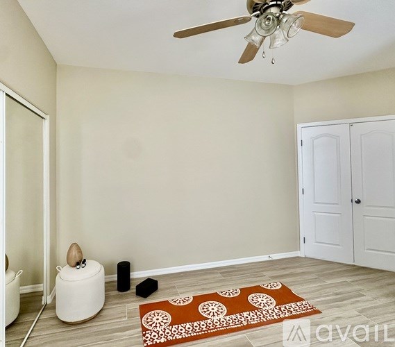 A room with a ceiling fan, a rug, and a speaker on the floor.