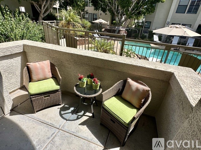 Two chairs and a table with flowers on a patio.