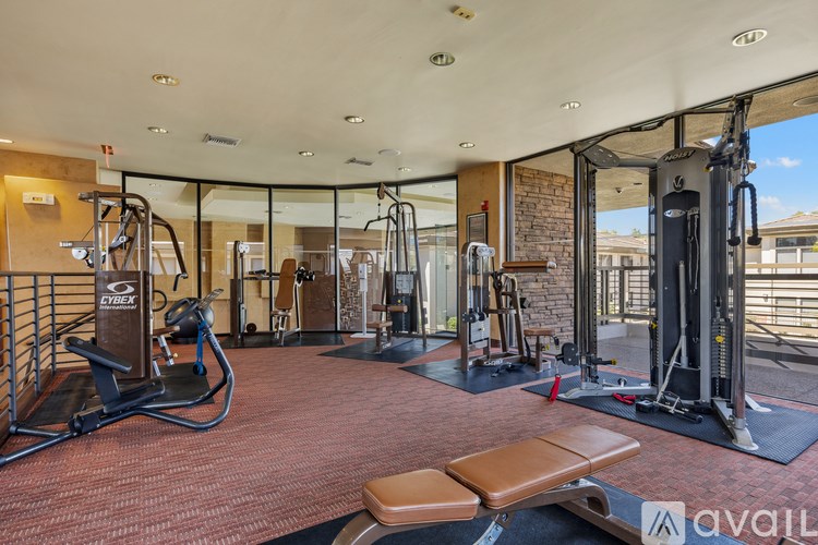 A gym with a variety of equipment including a treadmill, weights, and a bench.