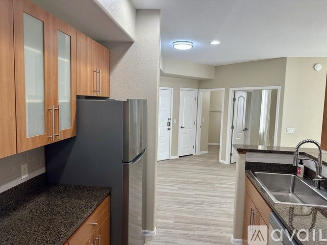 A kitchen with a black refrigerator and wooden cabinets.