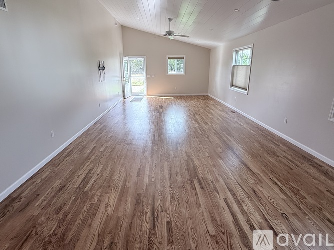 A spacious room with wooden flooring and a ceiling fan.