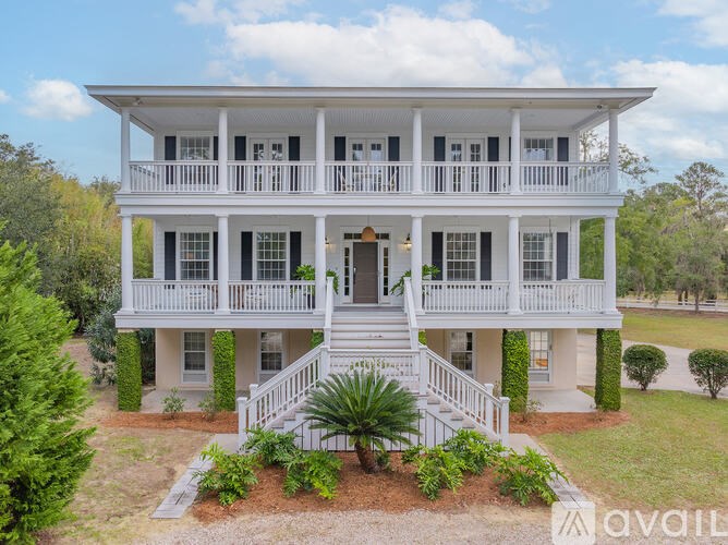 A white two-story house with a balcony on the second floor.