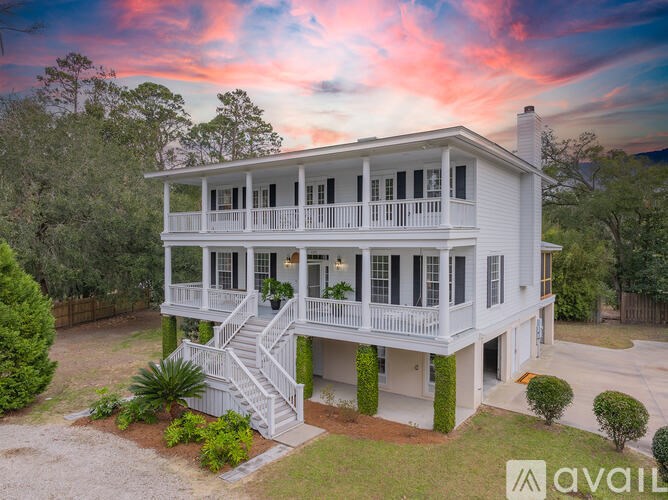 A white two-story house with a balcony and a staircase leading to the second floor.