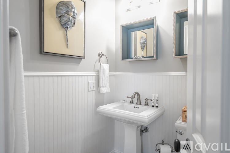 A white sink in a bathroom with a mirror and a shell on the wall.