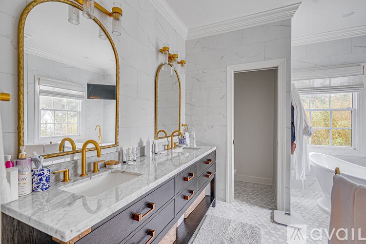 A bathroom with a marble countertop and gold fixtures.