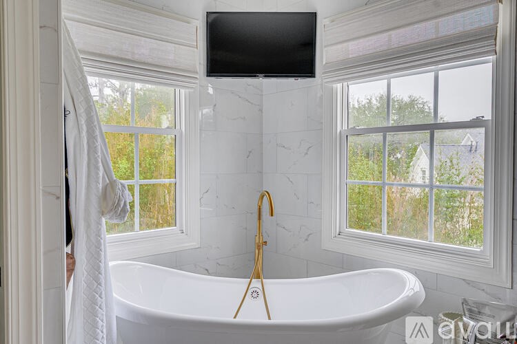 A white bathroom with a tub and a window.