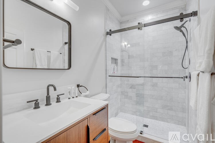 A bathroom with a white sink, toilet, and a glass shower door.