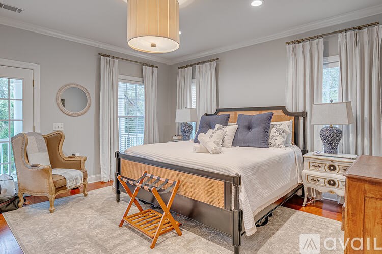 A bedroom with a large bed, a chair, and a lamp.