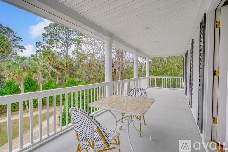 A balcony with a table and chairs overlooking a forest.