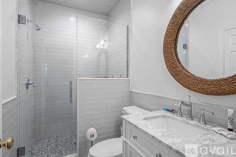 A bathroom with a white toilet, a white sink, and a round mirror.