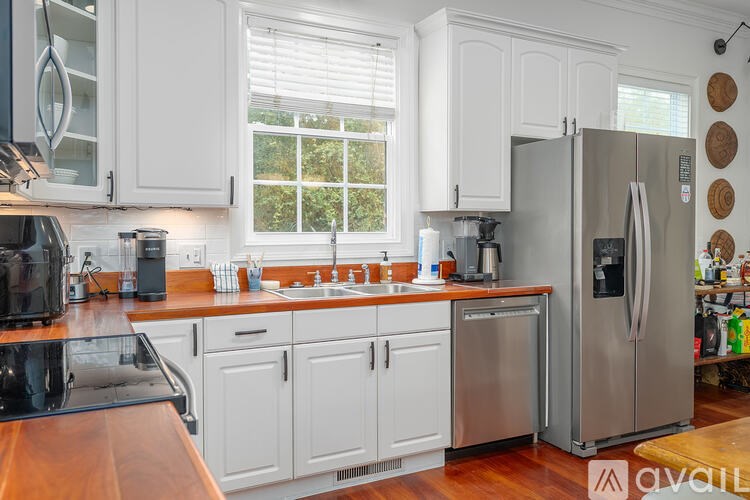 A kitchen with white cabinets and a wooden counter top.