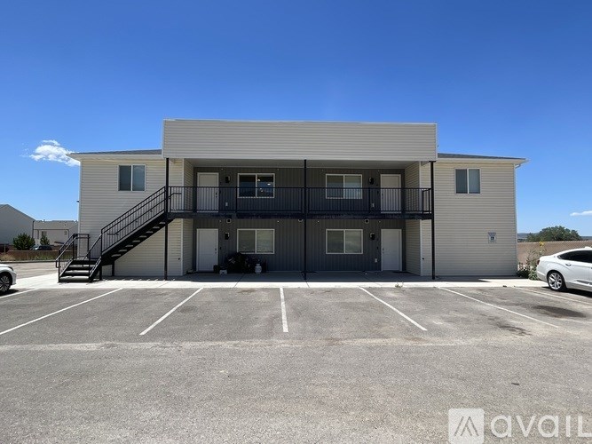 A two-story building with a balcony and a car parked in front.