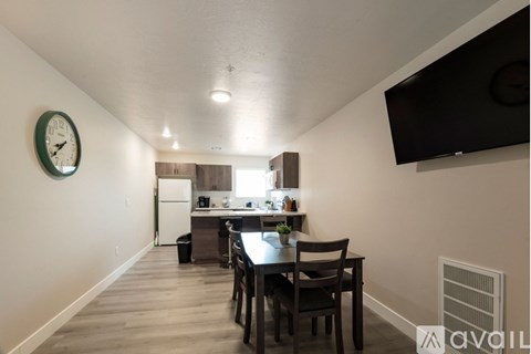 A kitchen with a table and chairs in the foreground and a clock on the wall.