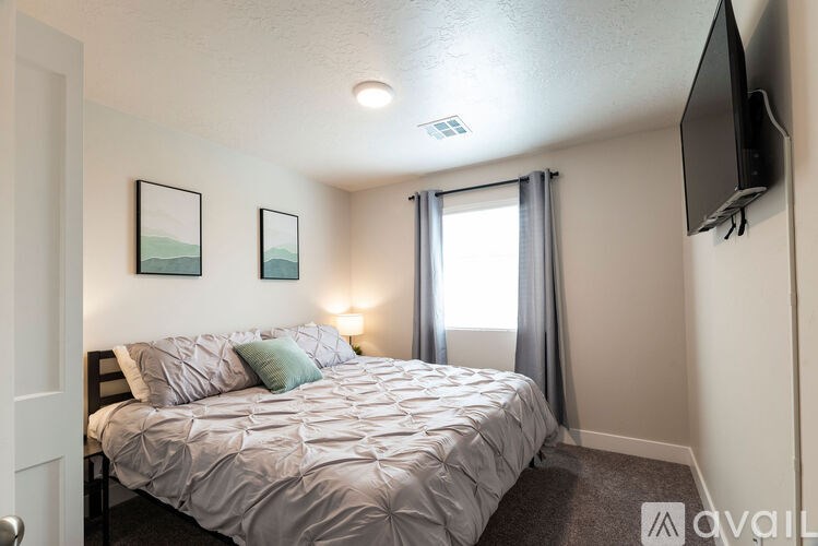 A bedroom with a bed, a television, and two pictures on the wall.