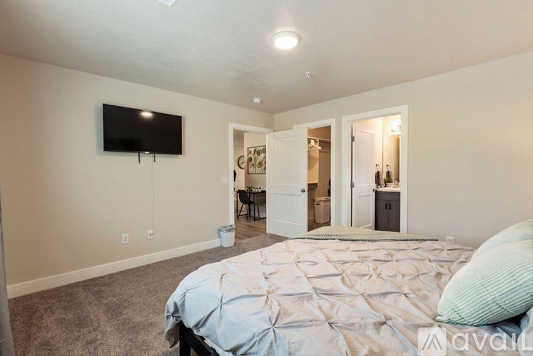A bedroom with a large bed and a flat screen TV mounted on the wall.