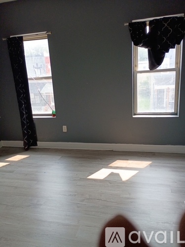 A room with a grey wall and a window with a black curtain.