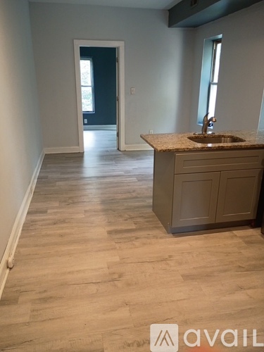 A kitchen with a sink and wooden floors.