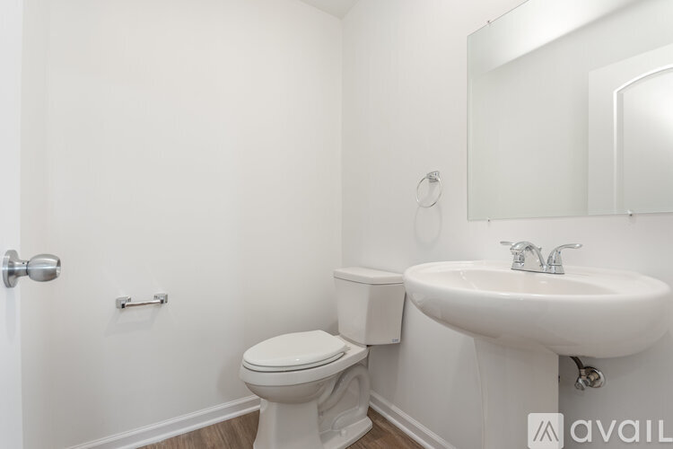 A white bathroom with a toilet, sink, and mirror.
