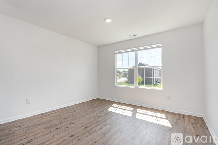 A spacious room with wooden flooring and a large window.