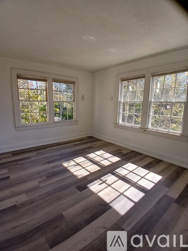 A room with wooden floors and two windows.