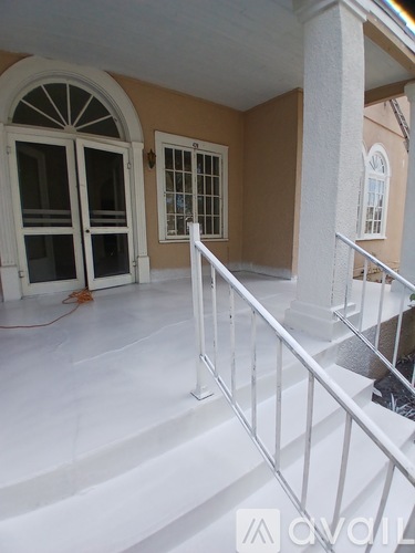 A white staircase with a metal railing leads to a second floor.
