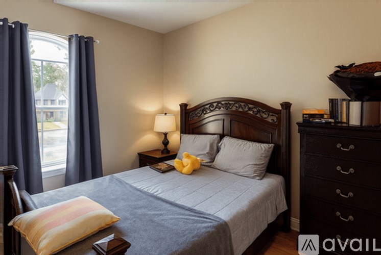A bedroom with a bed, nightstand, and window with curtains.