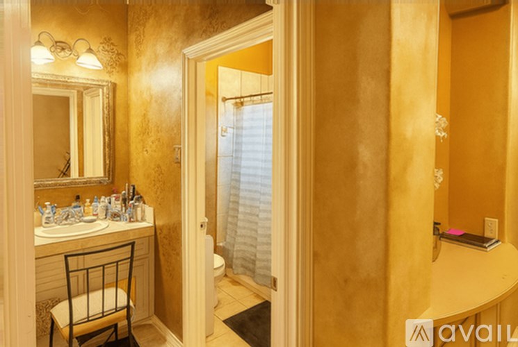 A bathroom with a sink, mirror, and chair.