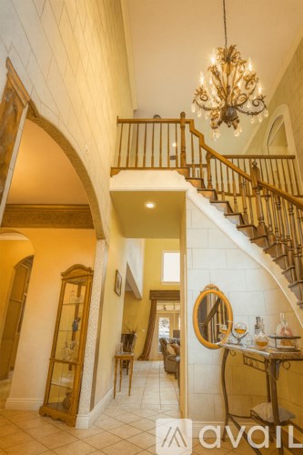 A large chandelier hangs over a staircase in a home.