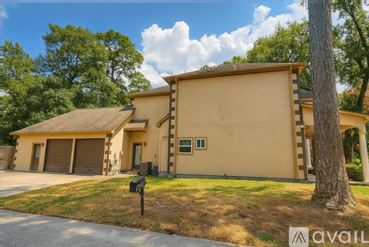 A beige house with a brown roof and a tree in front.