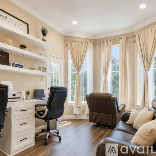 A home office with a black chair, a desk with a laptop and a printer, and a brown leather couch.
