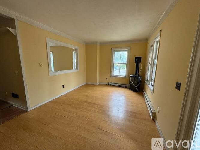 A room with wooden floors and a large mirror on the wall.