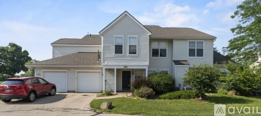 A two-story house with a garage and a red car parked in front.