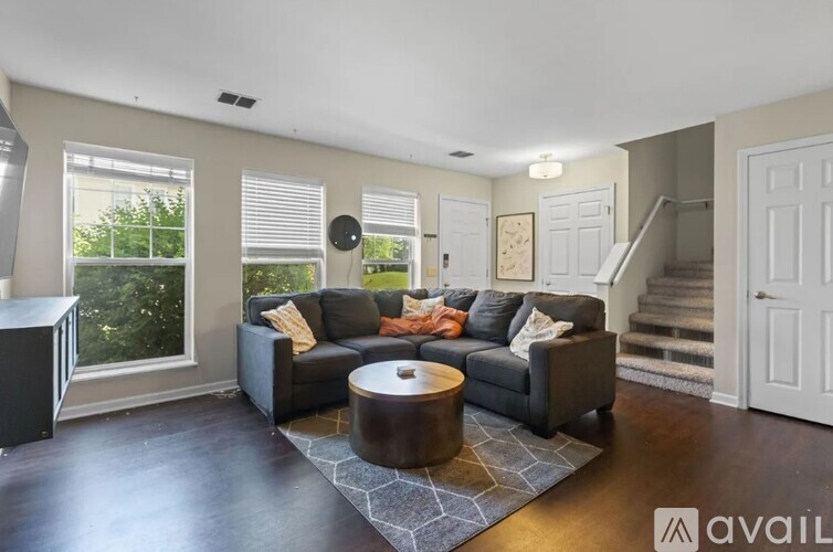 A living room with a black couch and a round coffee table.