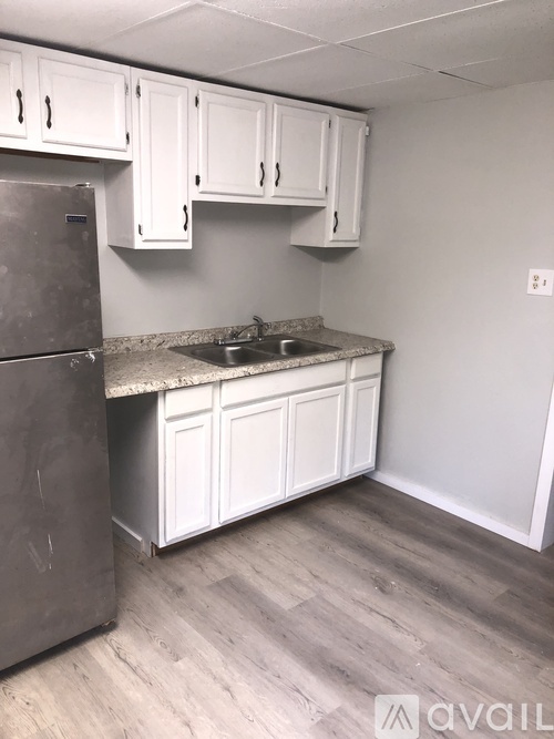 A kitchen with white cabinets and a stainless steel refrigerator.