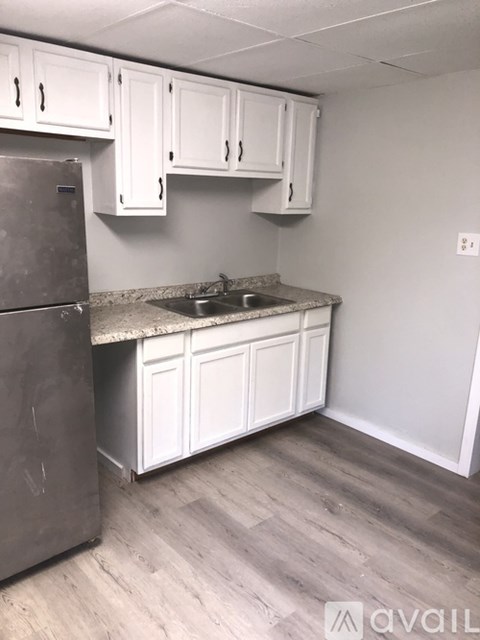 A kitchen with white cabinets and a stainless steel refrigerator.