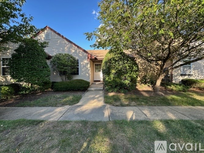 A house with a front yard and a tree in front of it.