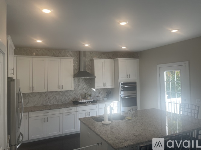 A kitchen with white cabinets and a wooden floor.