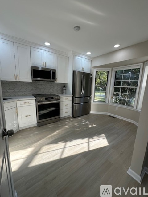 A kitchen with white cabinets and a wooden floor.