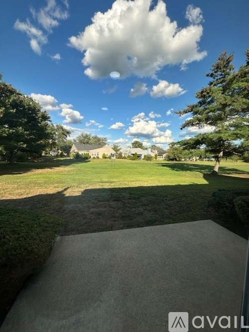 A clear sky with a few clouds over a green lawn.