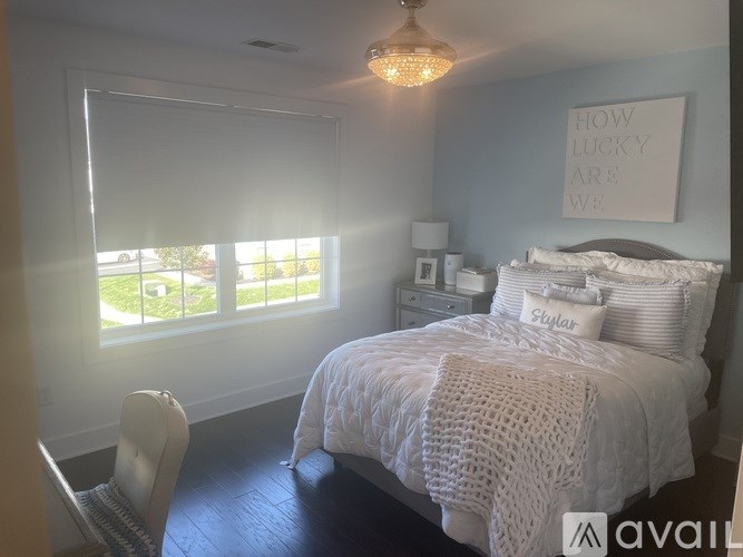 A bedroom with a bed, a chair, and a window with blinds.