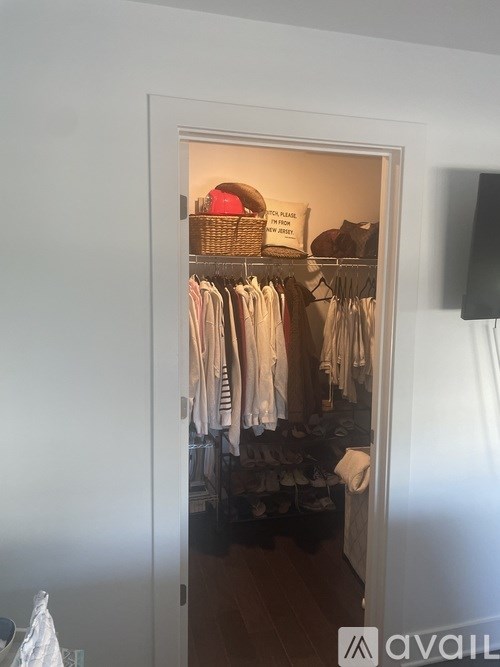 A white closet with clothes hanging inside.