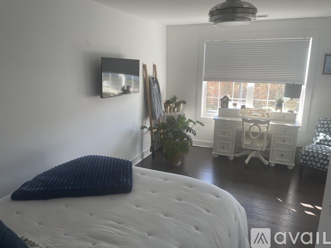 A bedroom with a white bed and a white dresser with a mirror.