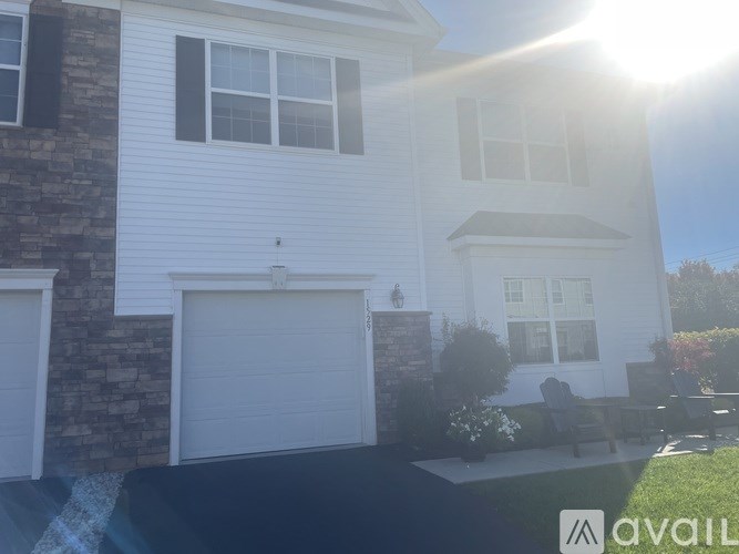 A house with a white garage door and a stone wall.