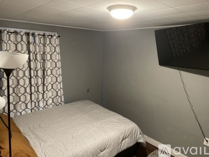 A bedroom with a bed, a lamp, and a curtain.