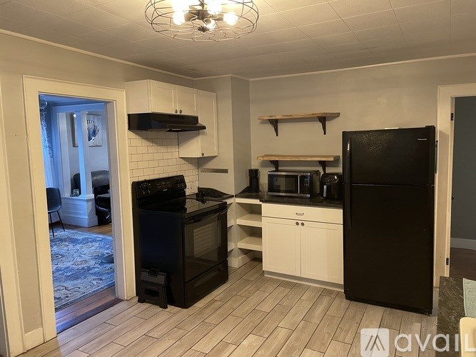 A kitchen with black appliances and white cabinets.